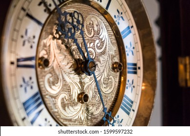 A closeup of a golden wall clock dial shimmering in the morning light with Baroque floral designs engraved