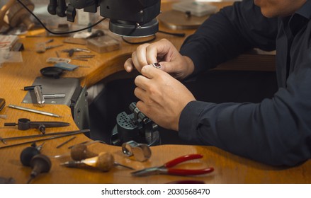 Close-up of goldsmith hand decorating precious ring with diamonds. Professional jeweler using special equipment. Gold jewelry production concept