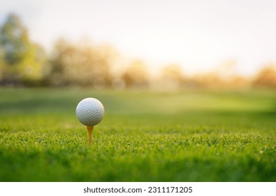 Close-up golf ball on tee with fairway golf course and sunrise background. - Powered by Shutterstock