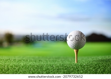 Close-up golf ball on tee with fairway golf course background.