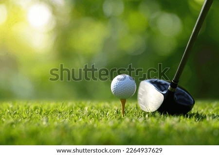 Close-up golf ball on tee with golf drivers at golf course.