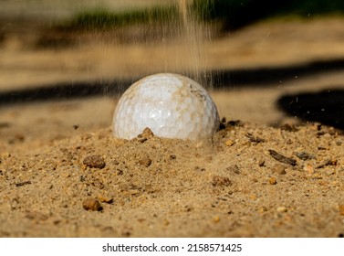 A Closeup Of A Golf Ball Stuck In The Sand