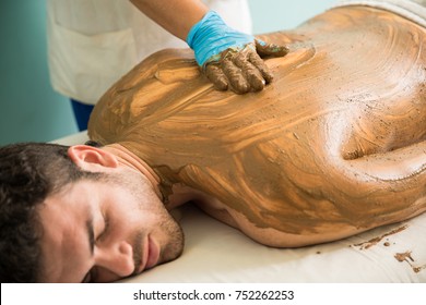 Closeup Of A Good Looking Young Man Getting A Mud Bath In A Wellness Clinic And Spa