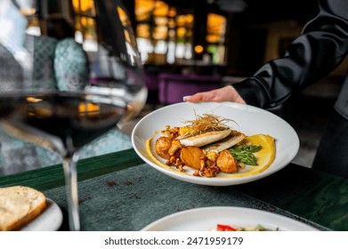 A close-up of a gourmet dish being served in an elegant restaurant, with a focus on the plated food and a blurred background enhancing the fine dining experience - Powered by Shutterstock