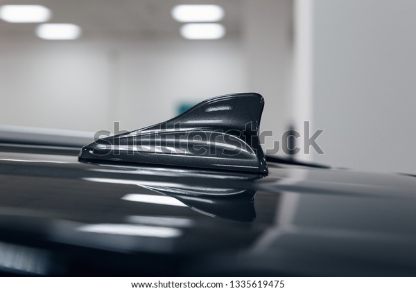 Close-up GPS antenna shark fin shape on a roof of car\
for radio navigation system. Antenna shark fin on blurry\
background. Car detail\
