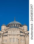 Close-up of a grand Istanbul mosque with intricate stonework, a majestic dome, and golden spire details, set against a vivid blue sky—showcasing elegance in Islamic architecture.