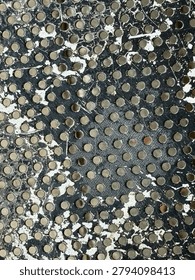 Close-up of a gray and white textured surface with numerous small circular indentations.
