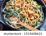 close-up of Green Bean Casserole topped with crispy fried onions in a black dish with spoon,  american cuisine, view from above