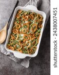 Close-up of Green Bean Casserole topped with crispy fried onions on the baking dish on the table. Vertical top view from above
