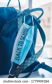 Closeup Of A Green Bookbag And A Blue Surgical Mask With The Text Back To School Written In It, Depicting The Need To Prevent The Infection At School In The Covid-19 Pandemic Situation