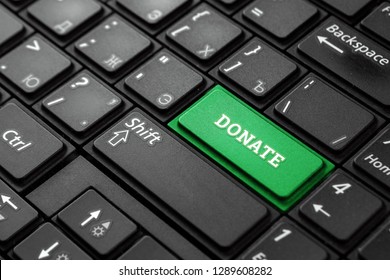 Closeup of a green button with the word Donate, on a black keyboard. Creative background, copy space. Concept magic button, investor, salary, blogger, blood donation, homeless, charity.