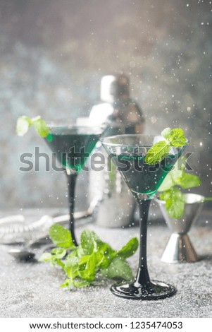 Closeup of green cocktails in martini glasses with mint leaves over gray background