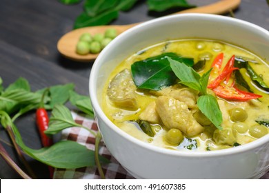 closeup green curry with chicken (Kang Keaw Wan Gai) with herb on wooden background, Thai local food