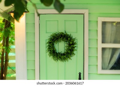 CloseUp Of Green Door And Decorative Wreath. Autumn Welcome Wreath, Decorating Front Door Home. House Door With Decor With Leaves Wreath. Autumn Cozy Decor Home For Thanksgiving. Summer Decor Door 