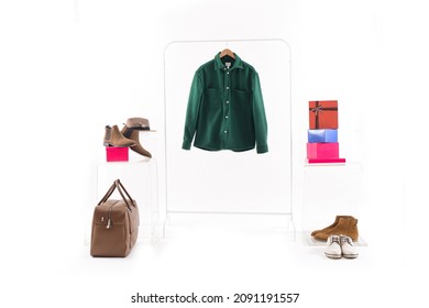 Closeup Of A Green Dress Shirt On A Wooden Hanger With Stacked Gift Box With Handbag, Hat, Brown Boots 

