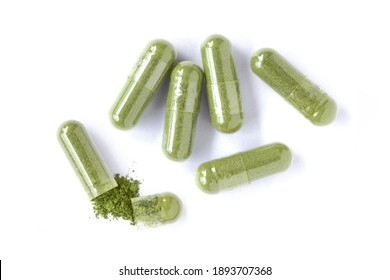Closeup green herbal powder medicine capsules pills isolated on white background. Top view. Flat lay  Macro