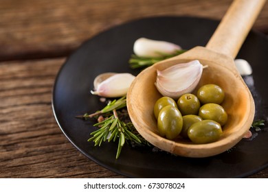 Close-up of green olives, rosemary and wooden ladle on table - Powered by Shutterstock