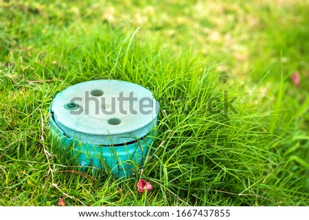 Closeup of green plastic pipe with cover on green grass lawn.