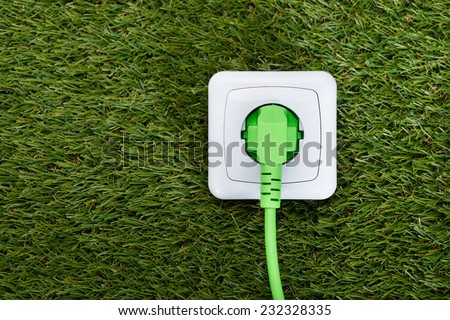 Closeup of green plug in outlet on grass