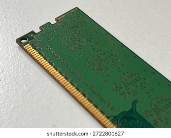 Close-up of green RAM memory module showing golden contact pins and intricate circuit board traces. High-tech computer hardware component isolated on white background. Ideal for technology, data storage, PC hardware upgrades, and digital infrastructure concepts.