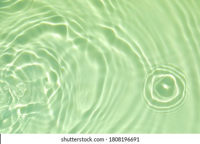 Closeup of green transparent clear calm water surface texture with splashes and bubbles. Trendy abstract summer nature background. Mint colored waves in sunlight. Copy space.