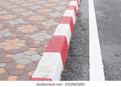 Close-up grey street and red-white marking parallel with white straight line. Red and white marking sign on the road. No parking, sign white and red on footpath road. Traffic line, traffic law concept