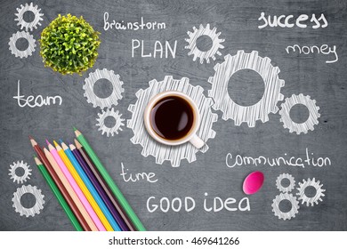 Closeup of grey wooden desktop with plant, coffee cup, colorful pencils, eraser and multiple cogwheel sketches. Teamwork concept - Powered by Shutterstock