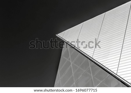 A closeup greyscale shot of a metal glass building under a clear sky