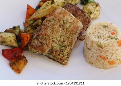 A Closeup Of Grilled Fish Entree With Rice Pilaf And Fresh Vegetables On A Plate