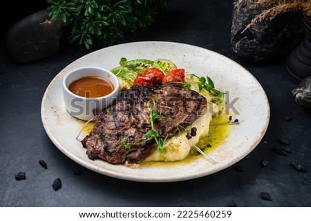 Closeup of grilled rib eye beef steak served with mash potato and vegetables.Ribeye beef steak with mashed potatoes and sauce in a plate.