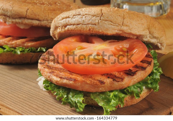 Closeup of grilled salmon burgers with a mug\
of beer in the\
background