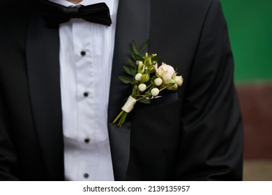 close-up of the groom's boutonniere, bow tie, white shirt and black jacket. Groom's boutonniere with white flowers. Boutonniere on the groom's jacket. Groom's boutonniere
