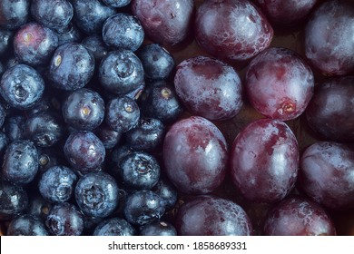 Close-up of a group of blueberries in the middle of the image and another group of black grapes. Split-screen. Fruit and health.