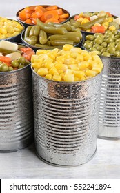 Closeup Of A Group Of Canned Vegetables. Seven Cans Of Mixed Veggies, Corn, Peas, Carrots And Green Beans.