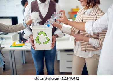 Close-up of a group of employees recycling the trash by collecting it in a bin in a pleasant atmosphere in the office. Employees, job, office