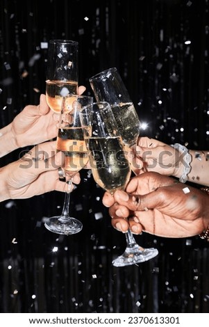 Closeup of group of friends toasting with champagne glasses at party against glittering background with confetti Stock photo © 