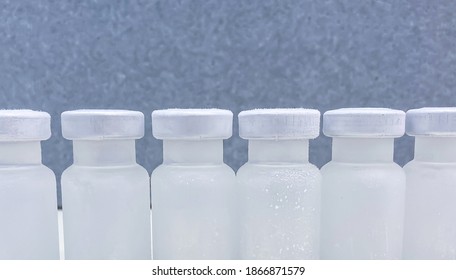 Closeup Of A Group Of Frosted Vials With Crimp Caps Taken Out From A Container With Dry Ice After Professional, Medical Transport. Selected Focus.