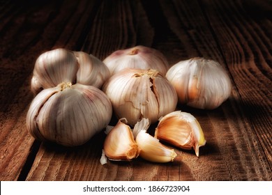 Closeup Of A Group Of Italian Garlic Cloves On A Dark Rustic Wood Table. Light Painting Still Life.