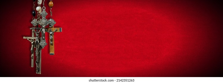 Close-up Of A Group Of Metal And Wooden Crucifixes And Rosary Beads On Red Velvet Background With Copy Space.