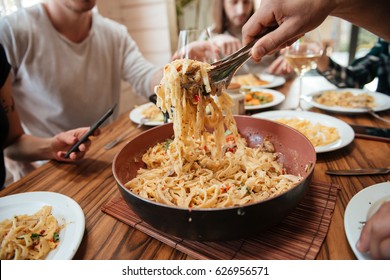 Closeup Of Group Of People Eating Pasta On The Kitchen At Home