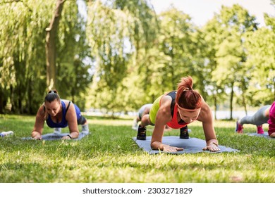 Close-up of group of women exercising during outdoors fitness class in park. Plank exercise for abs muscle. - Powered by Shutterstock