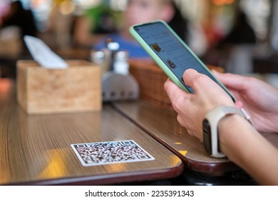 Closeup of guest hand ordering meal in restaurant while scanning qr code with mobile phone for online menu. - Shutterstock ID 2235391343