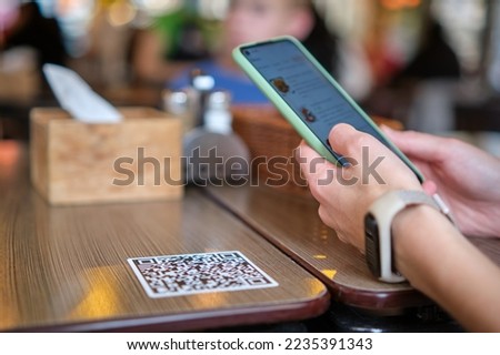 Closeup of guest hand ordering meal in restaurant while scanning qr code with mobile phone for online menu.
