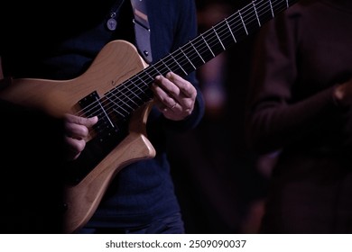 Close-up of a guitarist's hands playing during a jazz concert, with blurred background. - Powered by Shutterstock