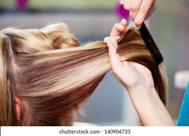 Closeup Of Hair Dresser Combing Client's Hair In Salon