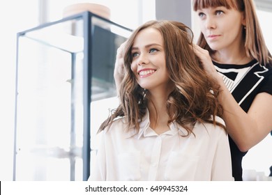 Closeup hairdresser makes hairstyle for young woman in beauty salon - Shutterstock ID 649945324