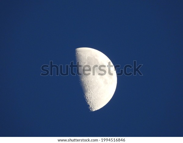 closeup of half\
moon with blue sky\
background