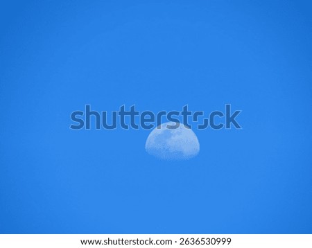 A closeup of a half moon at daylight in the cloudless sky