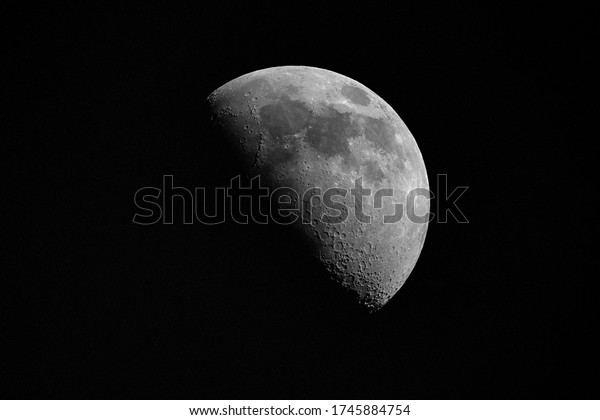Close-up of the\
half moon or first quarter moon against night sky. Astro and\
science background isolated on\
black.