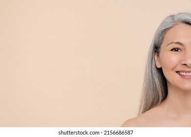 Closeup half-cropped portrait of a mature middle-aged shirtless naked woman smiling with toothy smile having grey hair and aging pure skin looking at camera. Beauty concept. Anti-aging rejuvenation